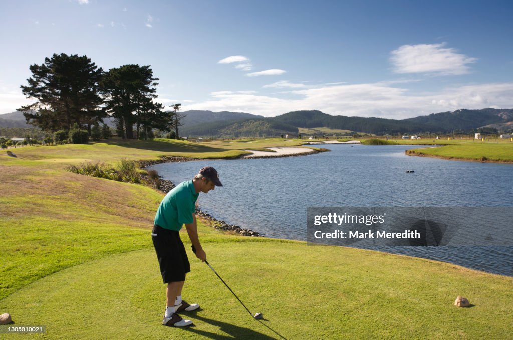 Golfer on tee by lake