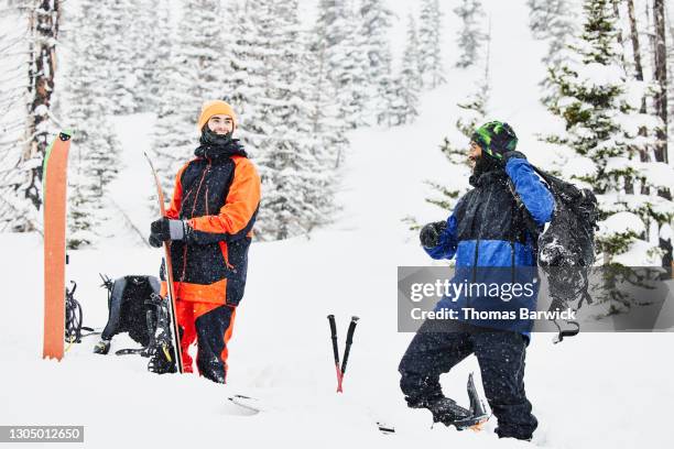 smiling splitboarders transitioning to uphill mode while riding in backcountry during snow storm - ski pants stock-fotos und bilder