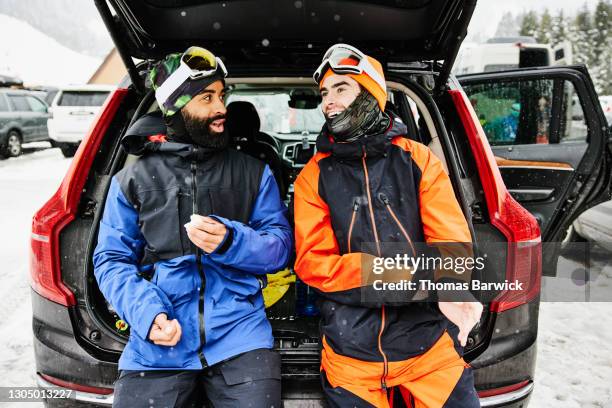 smiling snowboarders hanging out at back of car after day of riding - sport schutz stock-fotos und bilder