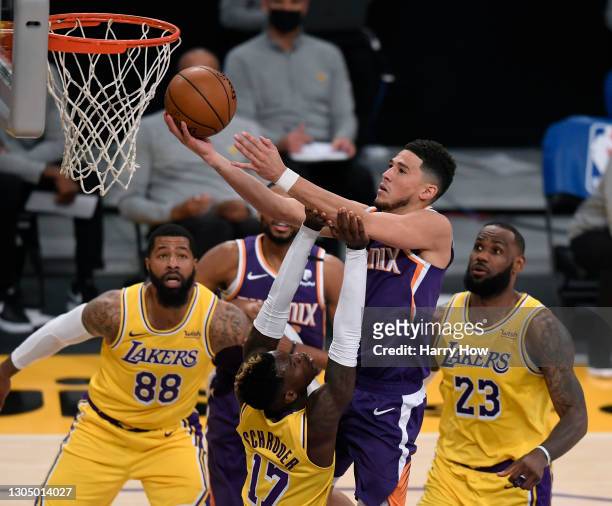Devin Booker of the Phoenix Suns scores on a layup over Dennis Schroder of the Los Angeles Lakers as LeBron James and Markieff Morris look on during...