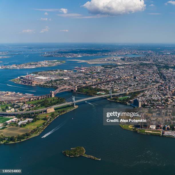 aerial view on robert fitzerald kennedy bridge, hell's gate bridge, and randalls island, with the distance panorama of upper manhattan behind, from helicopter. - astoria queens stock pictures, royalty-free photos & images