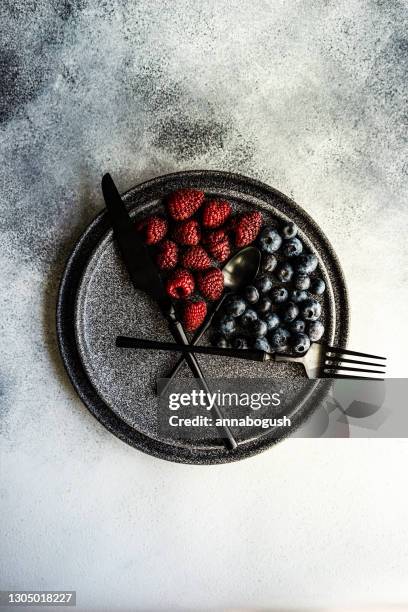 blueberries and raspberries arranged on a plate to convey intermittent fasting concept - fasten stock-fotos und bilder