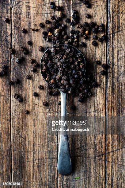 spoonful of black peppercorns on a  wooden table - black pepper stock pictures, royalty-free photos & images