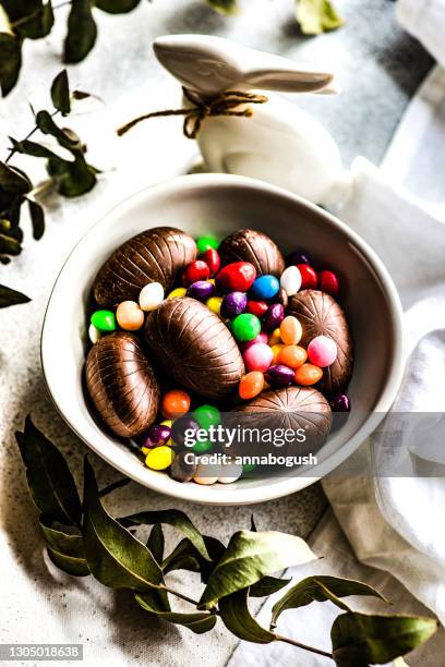 bowl of mixed chocolate easter eggs and an easter bunny ornament - chocolate egg stock pictures, royalty-free photos & images