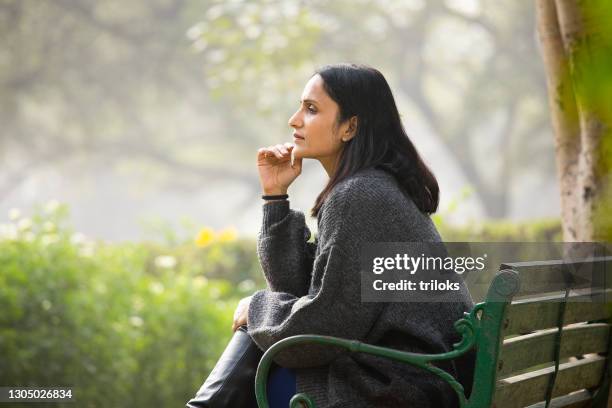 thoughtful woman sitting on bench - sitting alone stock pictures, royalty-free photos & images