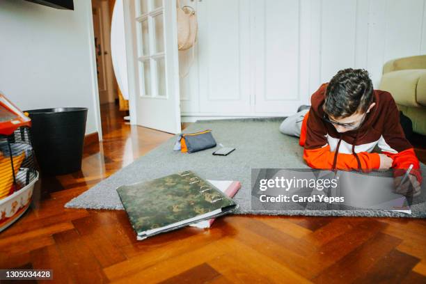 medium shot hispanic male student doing home works at home - room mates male stock-fotos und bilder