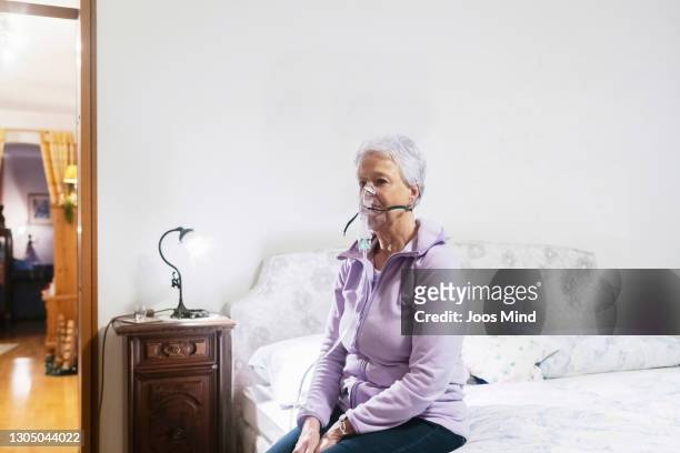 senior woman sitting on bed wearing respiratory mask - copd stock pictures, royalty-free photos & images