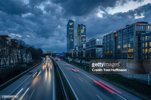 rush hour with high-rise office buildings and light trails at the autobahn a9 in munich - strassen nacht stadt stock-fotos und bilder
