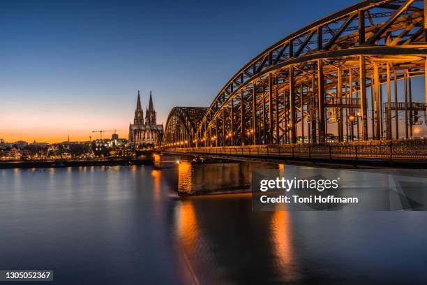 illuminated bridge hohenzollernbrücke at night with cologne cathedral - colonia renania fotografías e imágenes de stock