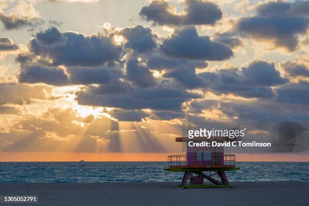 early morning sun bursting through clouds over the atlantic ocean, silhouette of iconic beach lifeguard station in foreground, miami beach architectural district, south beach, miami beach, florida, usa - barrier imagens e fotografias de stock