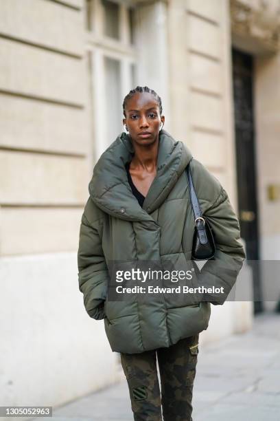 Model Skarla Ali wears a green oversized winter puffer coat with large collar, a black leather bag, green military khaki pants, on March 02, 2021 in...