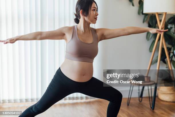 pregnant woman practices warrior 2 at yoga studio - 2 5 maanden stockfoto's en -beelden