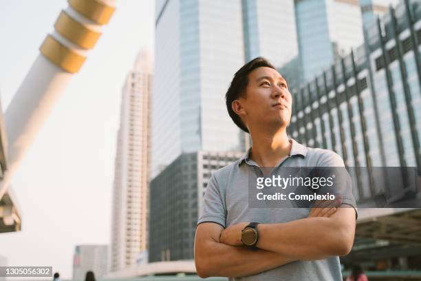 giovane asiatico in polo in attesa del futuro in alto edificio sfondo esterno - vietnamese ethnicity foto e immagini stock