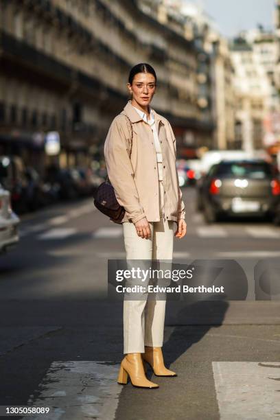 Maeva Giani Marshall wears a beige jacket with printed sentence "Drôle de Monsieur", a white shirt, white top, white pants, pale brown high heels...