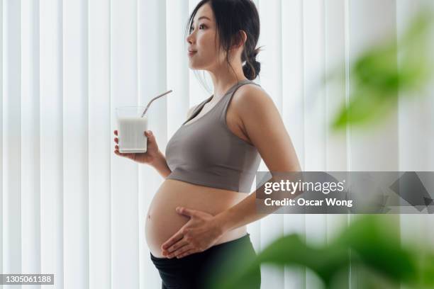 young woman taking rest and having a glass of fresh milk after a yoga session at home - milk plant stockfoto's en -beelden