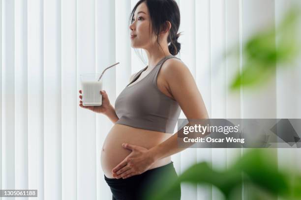 young woman taking rest and having a glass of fresh milk after a yoga session at home - calcio sport imagens e fotografias de stock