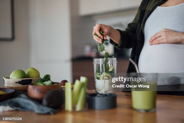 pregnant woman putting raw ingredients into a blender to make fresh homemade fruits smoothie - juicing stock pictures, royalty-free photos & images