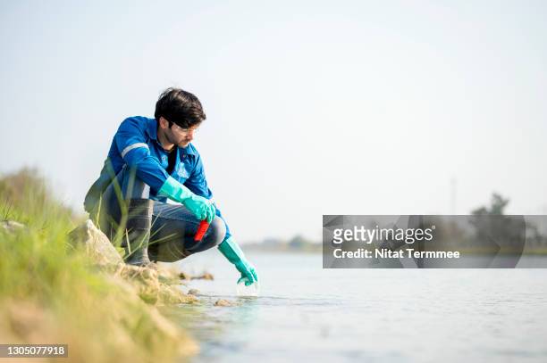 scientist in white safety suit examining polluted waste. environment scientist examining water and collecting water samples (ph value). - mass unit of measurement stock-fotos und bilder