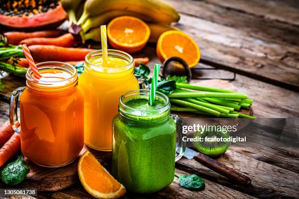 healthy fruits and vegetables smoothies on rustic wooden table - sumo de vegetais imagens e fotografias de stock