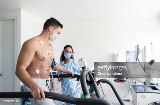 verpleegster die een patiënt controleert die een spanningstest doet terwijl het dragen van gezichtsmaskers - treadmill test stockfoto's en -beelden
