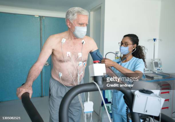 フェイスマスクを着用しながらストレステストを行うシニア患者を監視する看護師 - stress test ストックフォトと画像
