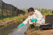 A technician in full body protective suit measure ph of sample of water