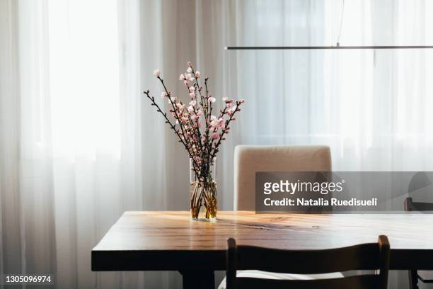 almond blossom twigs in a vase on wooden table in living room. - table stock-fotos und bilder