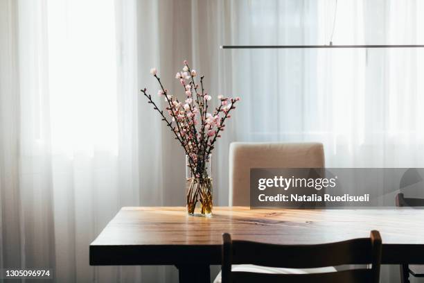 almond blossom twigs in a vase on wooden table in living room. - table vase stockfoto's en -beelden