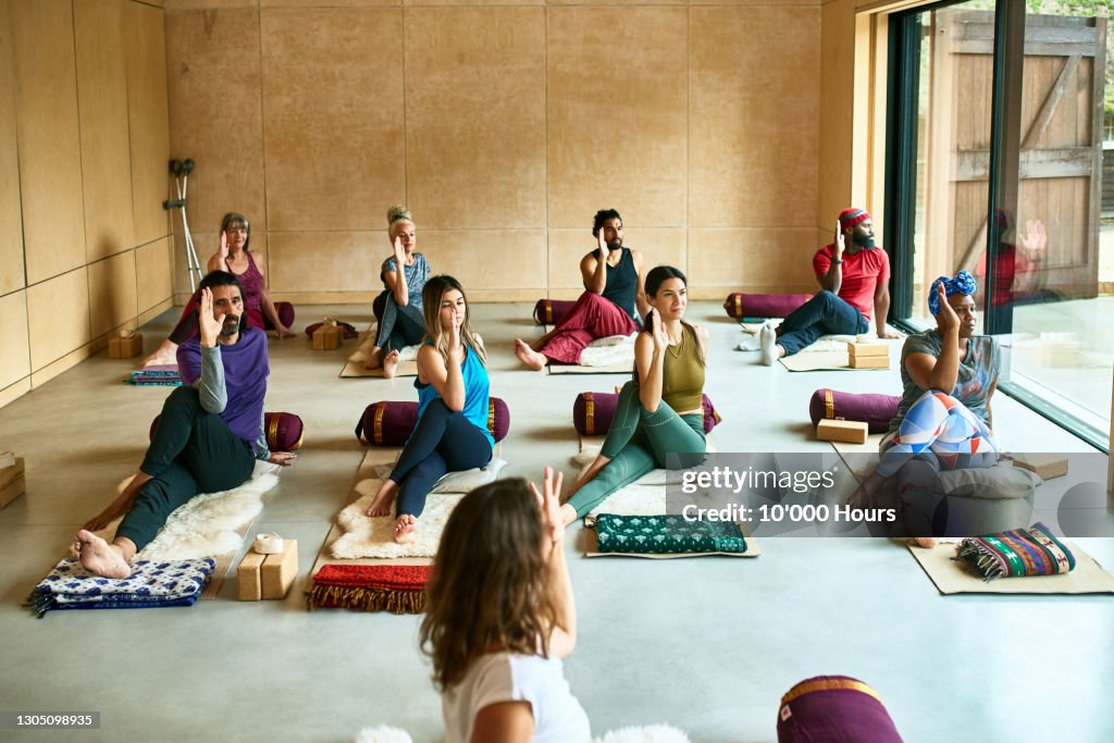 Yoga class on mats in studio in gentle twist