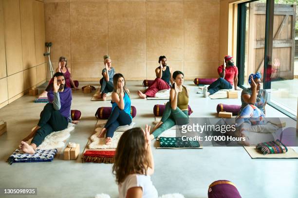 yoga class on mats in studio in gentle twist - senior yoga lady stock pictures, royalty-free photos & images