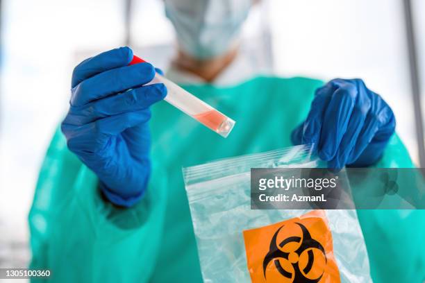 vrouwelijke arts zet monster van covid-19-test in biohazard bag - biohazard symbol stockfoto's en -beelden
