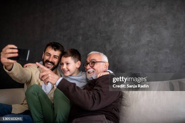 young man is taking selfie with his son and grandfather. - grandfather stock pictures, royalty-free photos & images