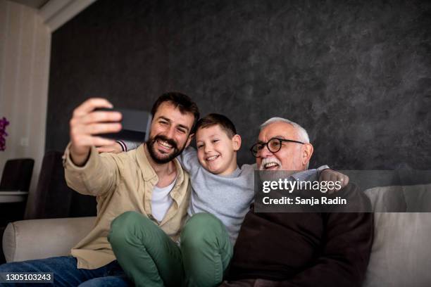 leende pojkar sitter på bäddsoffan och tar selfie. - three people bildbanksfoton och bilder