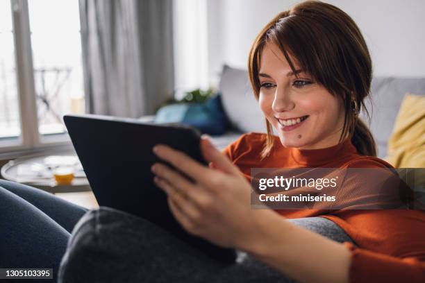 women in business: smiling young businesswoman using a digital tablet at home - work video call stock pictures, royalty-free photos & images