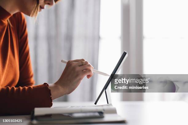 frauen in der wirtschaft: eine anonyme geschäftsfrau, die ein digitales tablet nutzt, während sie von zu hause aus arbeitet - digitized pen stock-fotos und bilder