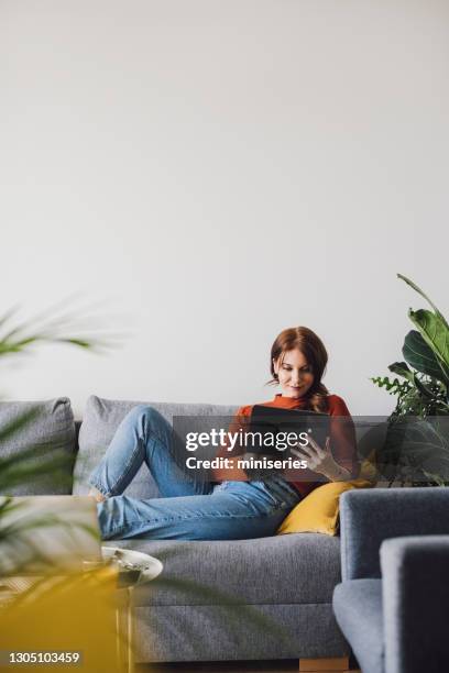 mujeres en el negocio: joven empresaria sonriente usando una tableta digital en casa - woman relaxing tablet fotografías e imágenes de stock