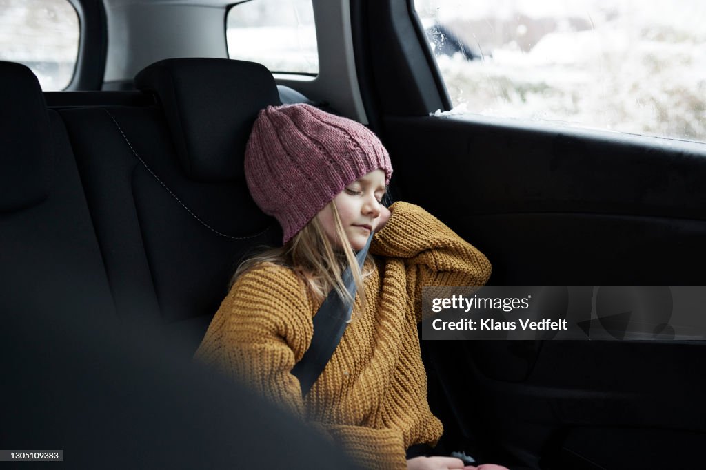 Girl sleeping while traveling in car during winter