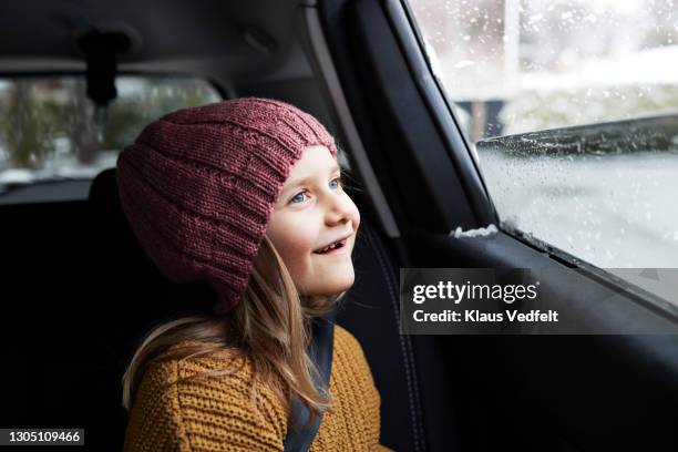 girl enjoying snowfall while traveling in car - winter car window foto e immagini stock