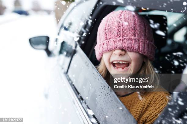 playful girl wearing knit hat in car - hoed stockfoto's en -beelden