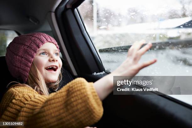 girl enjoying snowfall through car window - winter car window stock pictures, royalty-free photos & images