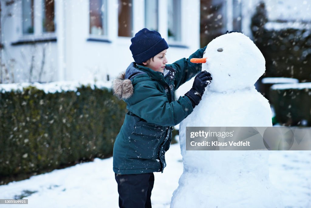 Boy making snowman in backyard
