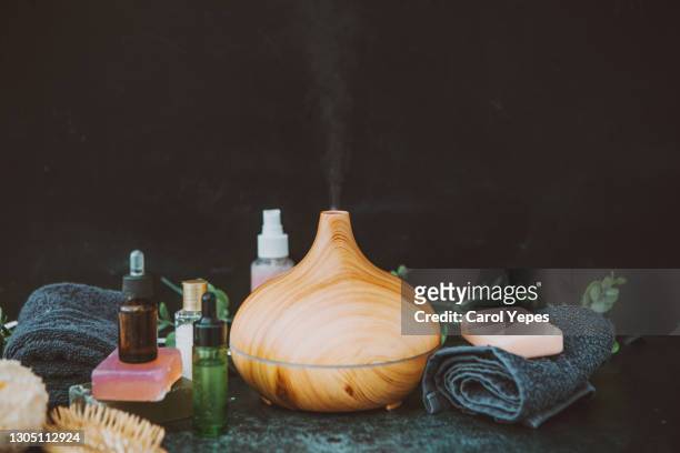 electric essential oils aroma diffuser, oil bottles and flowers on gray surface with reflection. - luft befeuchter stock-fotos und bilder