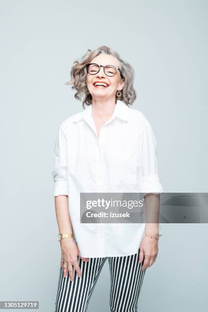 vrolijke hogere vrouw die overhemd en gestreepte broek draagt - white trousers stockfoto's en -beelden