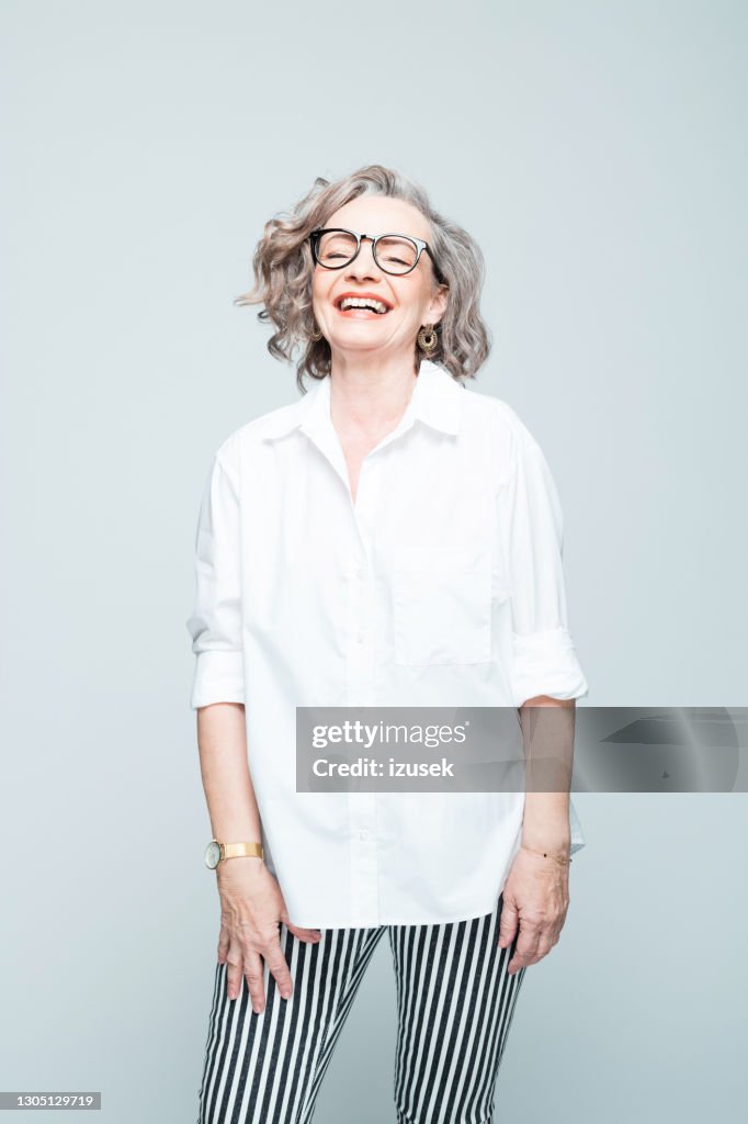 Cheerful senior woman wearing shirt and striped trousers