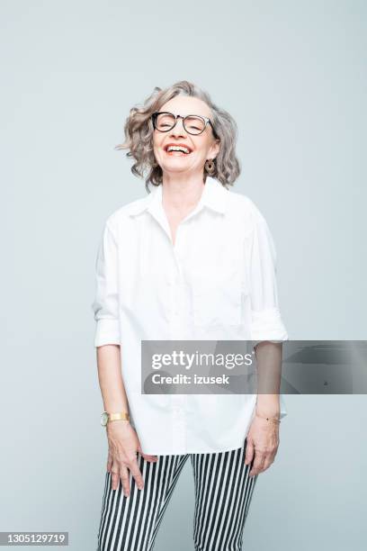 mulher idosa alegre vestindo camisa e calças listradas - 65 69 anos - fotografias e filmes do acervo