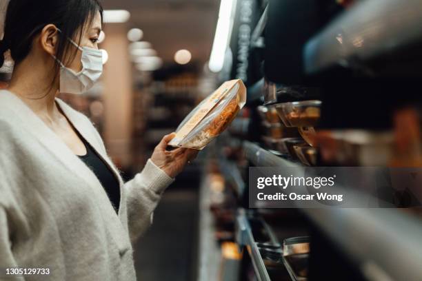 young woman getting food from cooling shelf in supermarket - auf dem tisch stock-fotos und bilder