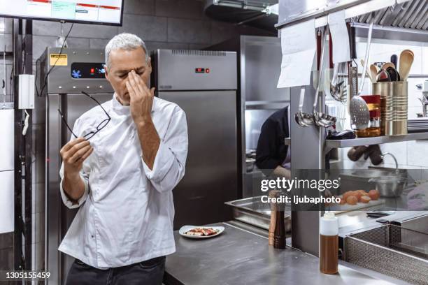 mature man feeling totally burnt out while standing in kitchen - restaurant manager covid stock pictures, royalty-free photos & images