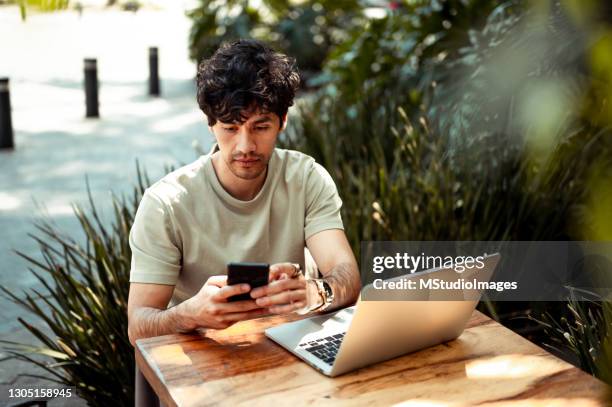 young man at coffee shop using mobile phone - hipster coffee shop candid stock pictures, royalty-free photos & images