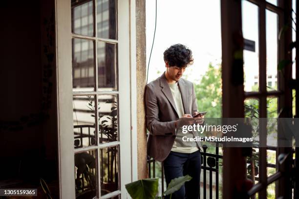 young man standing and using mobile phone - mexico nuit stock pictures, royalty-free photos & images