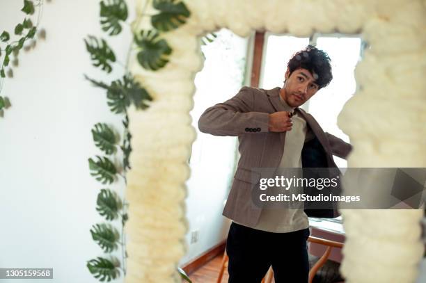 young man put on a jacket. reflection in the mirror - get dressed male stock pictures, royalty-free photos & images